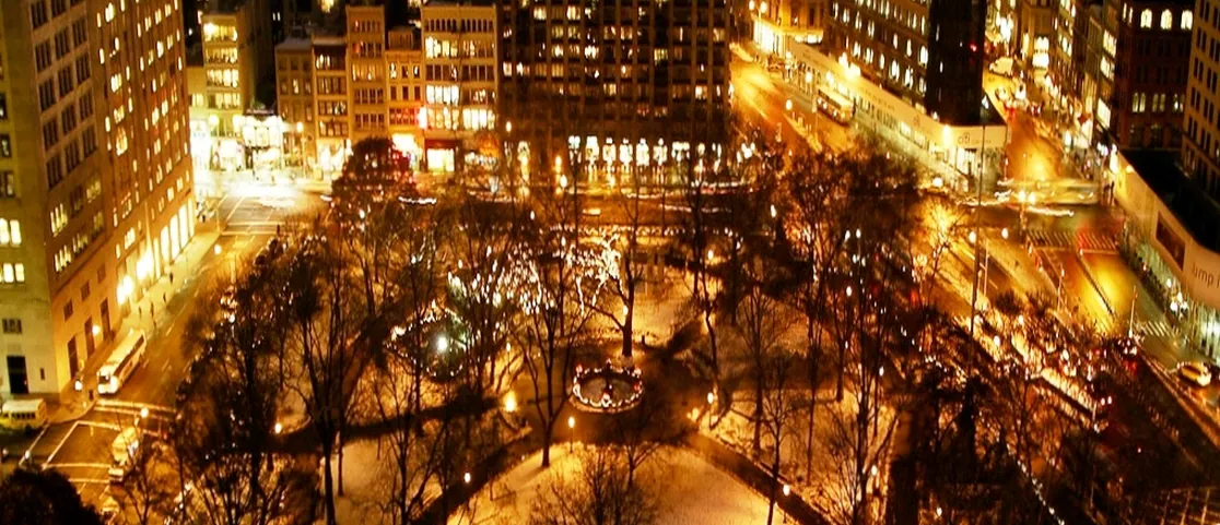 Madison Square Park illuminated paths and evening city lights from above at night in Manhattan