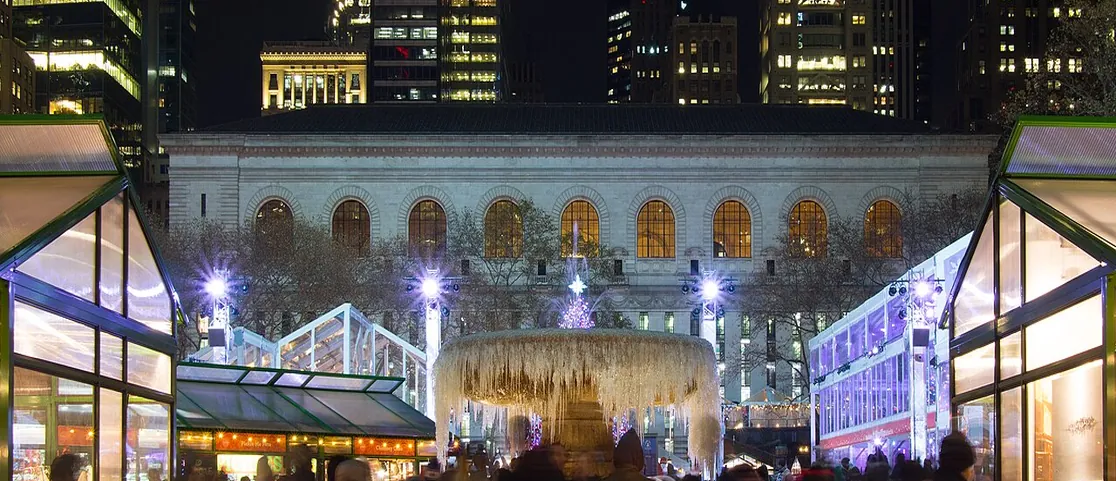 Bryant Park Winter Village illuminated glass kiosks and frozen fountain at night