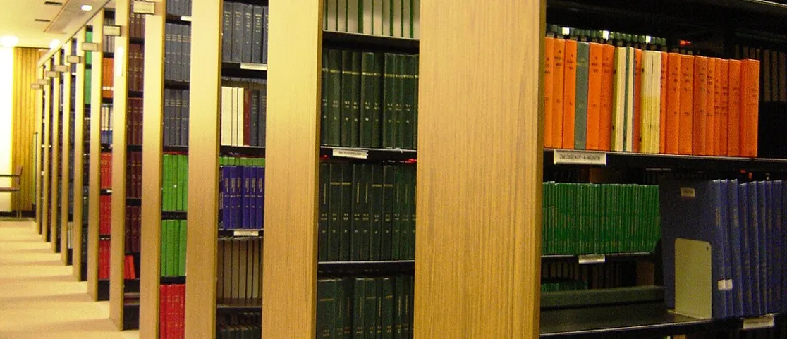 Floor to ceiling wooden bookshelves packed with used novels and art monographs