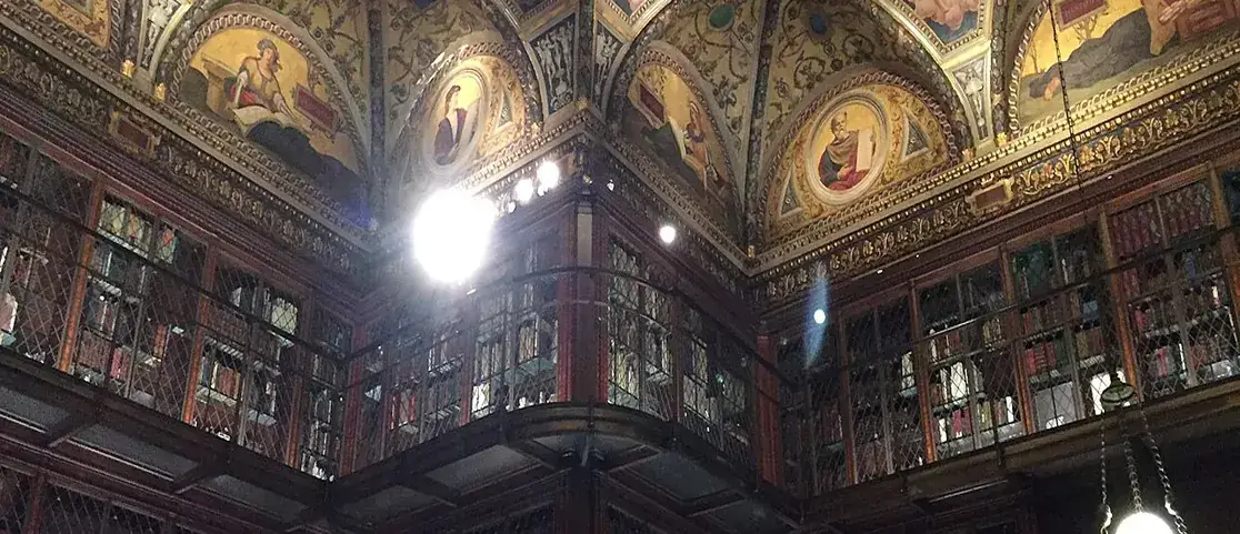 The soaring three-story East Room library at The Morgan Library and Museum with circassian walnut bookcases and ceiling frescoes