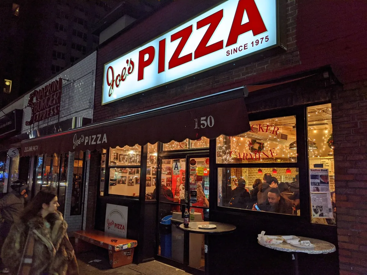 Wall of fame photos and busy slice counter at Joe’s Pizza on Carmine Street