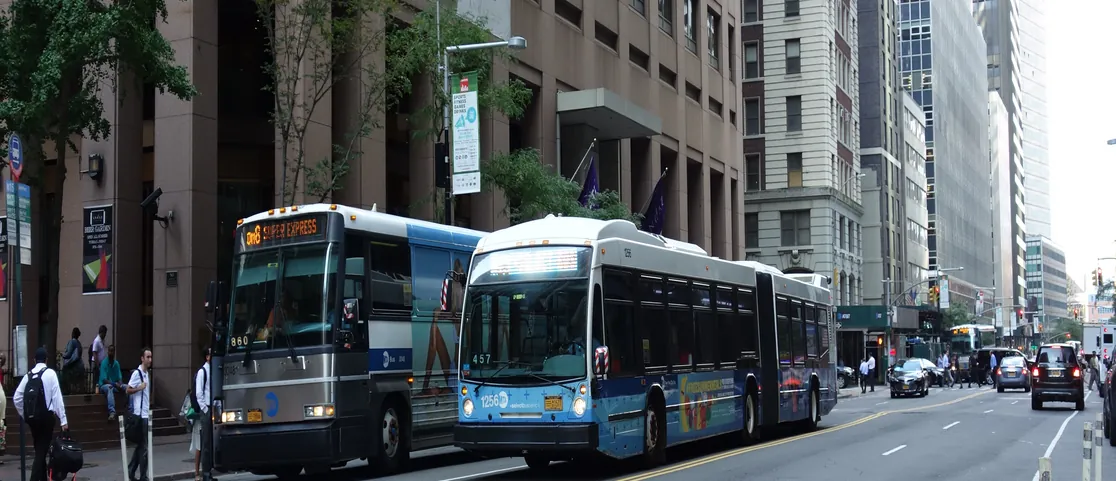 Low-floor NYC Select Bus Service SBS bus kneeling at a Manhattan curb with wide double doors opened for stroller boarding