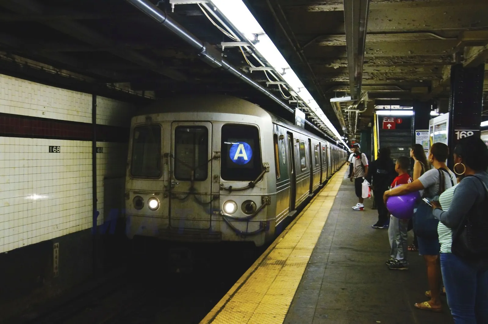 New York City Subway train arriving at an elevated station platform