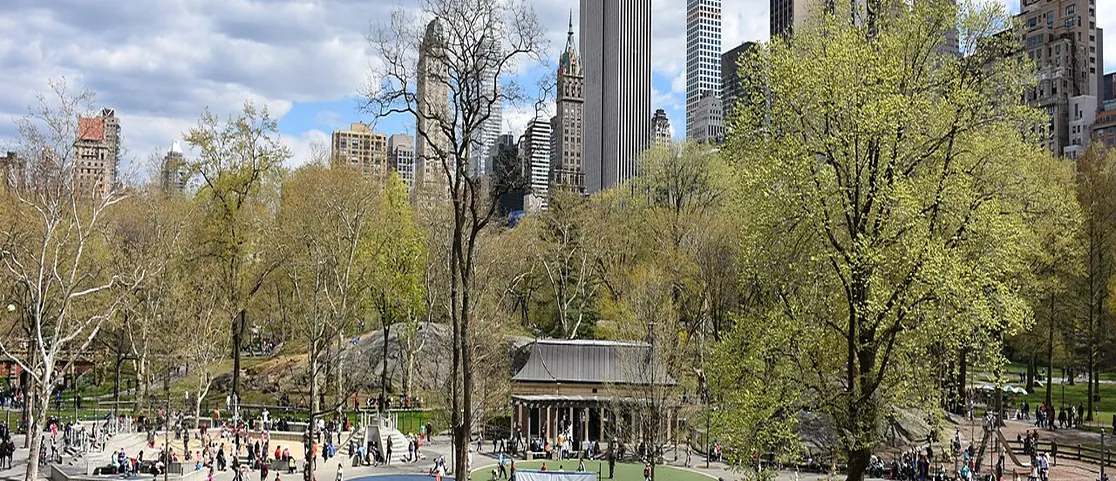 Heckscher Playground in Central Park shaded by mature oak tree canopies with children and parent seating