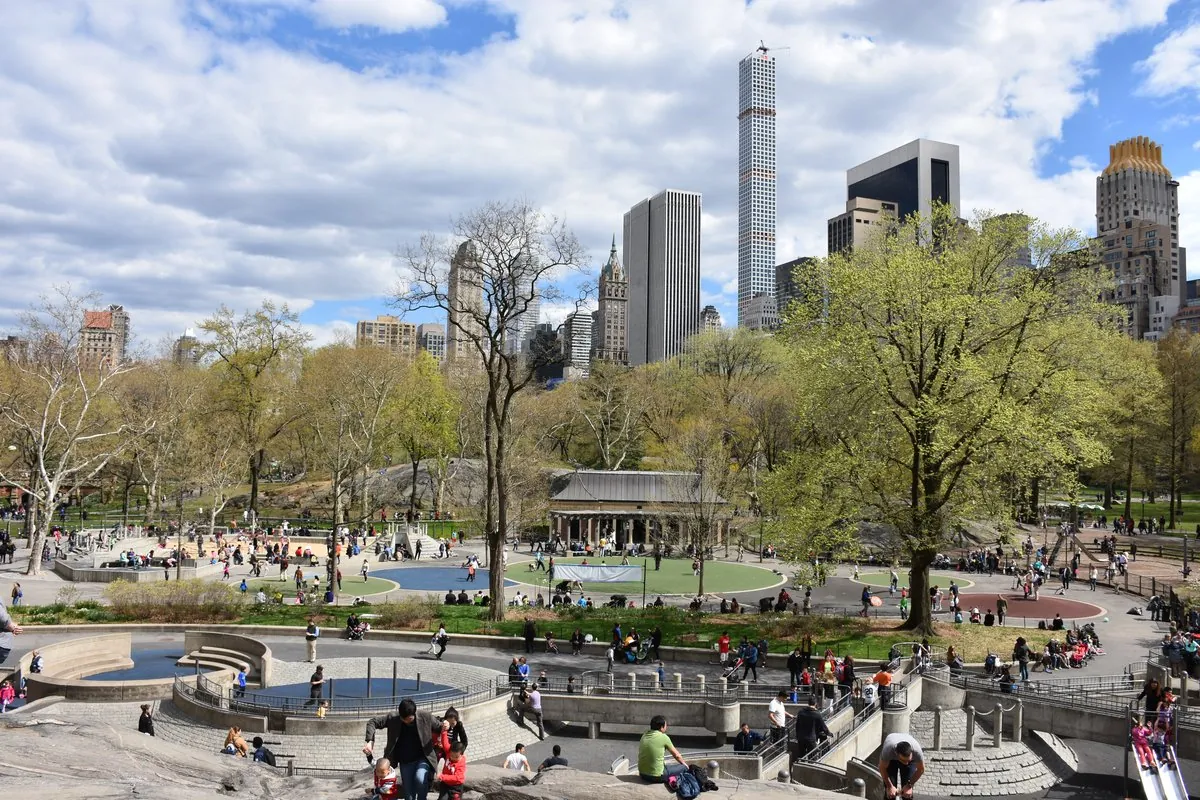 Children playing at Heckscher Playground with Central Park South skyline in background