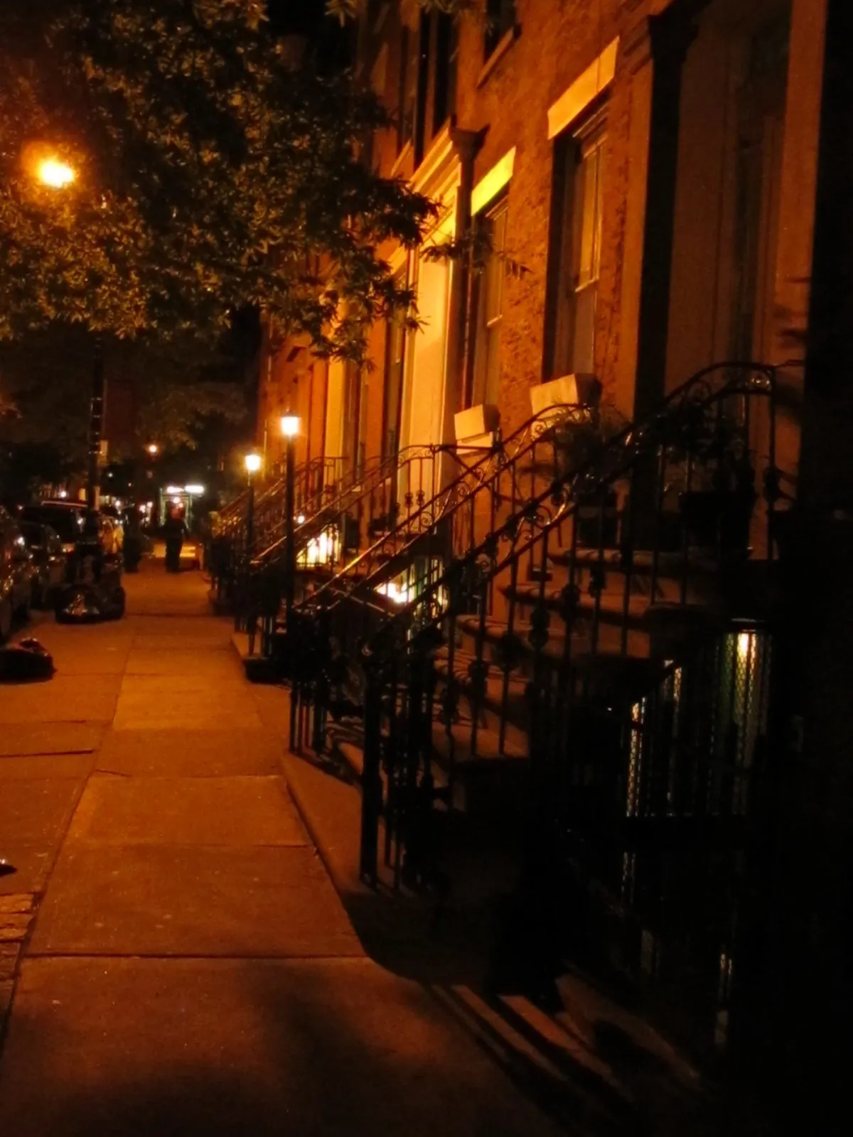 Historic brick townhouses with tree-lined sidewalks in Greenwich Village, Manhattan.